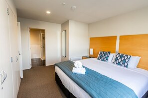 A hotel room with a bed, a bedside table, a mirror, and a wardrobe.