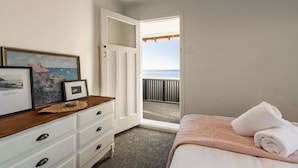 Un dormitorio con cama, cómoda, cuadro enmarcado y vista a la playa.