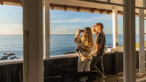 Una habitación con un ventanal grande que da al océano, techo de madera y vista al mar.