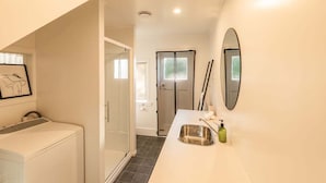 Un baño con lavadora, lavabo y espejo.