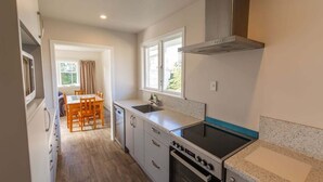 A compact kitchen with a dining area, a built-in oven, and a window providing natural light.