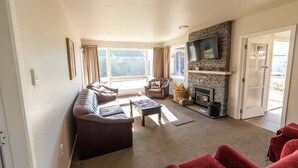 A living room with a sofa, armchair, fireplace, and a television mounted on a stone wall.