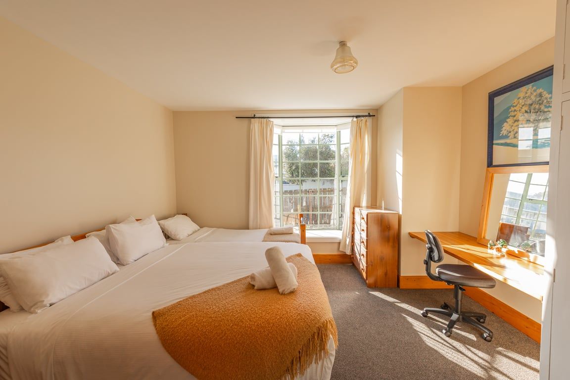 A hotel room with a large bed, a desk, and a window with curtains.