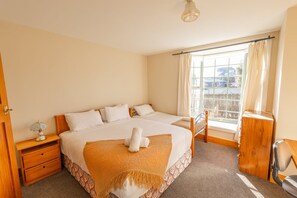 A hotel room with a large bed, a bedside table, a chair, and a window with curtains. - Charming Villa | Family Friendly | Handy to Town - KK14769 (Kaikoura)