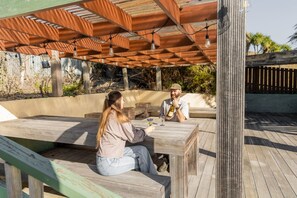Una terraza exterior de madera con una zona de estar integrada y una pérgola.