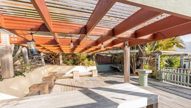 An outdoor deck with a pergola, wooden benches, and a table. - Charming Villa | Family Friendly | Handy to Town - KK14769 (Kaikoura)