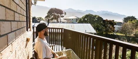 A person sitting on a balcony with a view of mountains and trees.