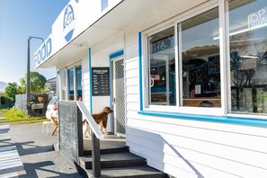 A food establishment with a signboard, a dog outside, and a menu board. - Coastal | Spacious | Mountain Views - KK21238 (Kaikoura)