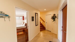A hallway with a bed, a staircase, and a door. - Coastal | Spacious | Mountain Views - KK21238 (Kaikoura)