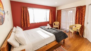 A bedroom with a bed, two chairs, a window, and curtains. - Coastal | Spacious | Mountain Views - KK21238 (Kaikoura)