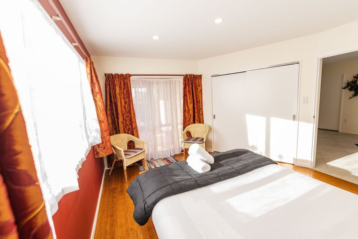 A hotel room with a bed, two chairs, a desk, and a wardrobe.