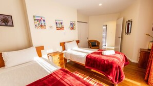 Ein Hotelzimmer mit zwei Betten, Holzboden und Bildern an den Wänden.