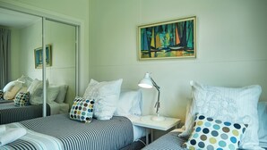 Habitación de hotel con dos camas, una mesita de noche, una lámpara y un cuadro en la pared.