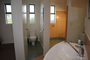 A bathroom with a toilet, a shower area, and a sink.