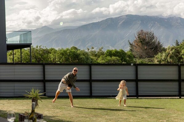 A man and a child playing in a backyard with a mountain view.