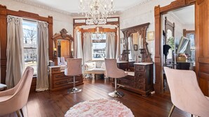 Una habitación con pisos de madera, un candelabro, un espejo grande y dos sillas rosas.