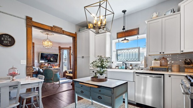 Una cocina moderna con armarios blancos, lavavajillas integrado y un comedor con mesa y sillas.
