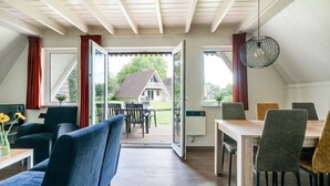A modern interior with a dining area, a sofa, and a table with chairs. - Mooie rustige woning Overijssel. (Gramsbergen)