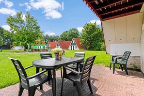 An outdoor patio with a table and chairs, a bottle of juice, and a potted plant.