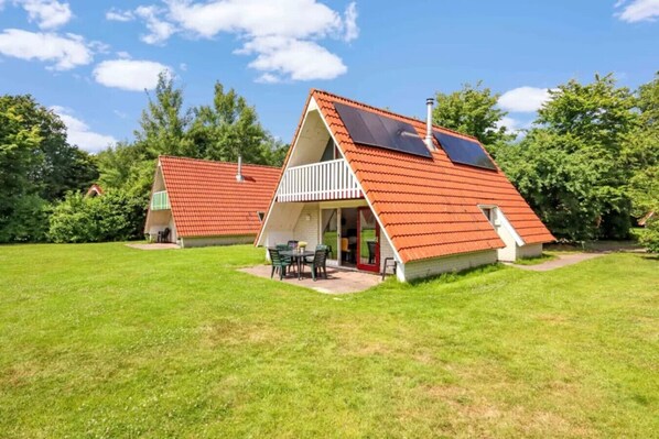 A house with a sloped roof, solar panels, and a small patio with outdoor furniture.