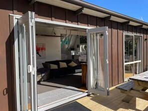 A modern house with an open sliding door leading to a living area with a sofa and a dining table.
