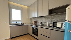 Eine moderne Küche mit grauen Schränken, einem eingebauten Ofen, einer Mikrowelle und einem Fenster.