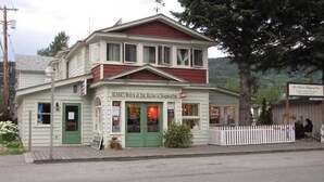 Ein zweistöckiges Gebäude mit einer grünen Tür und Fenstern, mit der Aufschrift 'OLIVIA'S Bistro am Historic Skaguay Inn'.