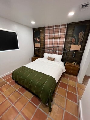 A bedroom with a bed, a window, a wall-mounted TV, and a decorative wall panel. - Pik-Pak D - "Tuff’s Place" (Marfa)
