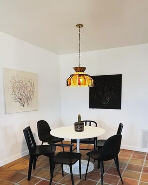 A dining area with a round table, four black chairs, a hanging pendant light, and two framed artworks on the walls. - Pik-Pak D - "Tuff’s Place" (Marfa)
