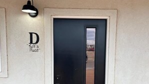 Une porte noire avec une petite fenêtre, un luminaire fixé au mur et une enseigne indiquant « Chez Duff ».