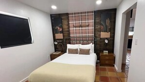Une chambre à coucher avec un lit, des tables de chevet, une fenêtre et un mur orné d’un motif à carreaux.