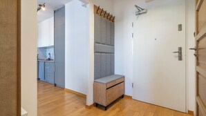 Un couloir avec un banc, une porte et une vue sur un espace cuisine.