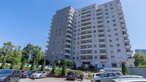 A multi-story residential building with balconies, a parking lot, and greenery. - Urban Chic Apartment (Katowice)