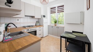 A modern kitchen with a wooden countertop, a built-in sink, and a dining area with a table and chairs. - Metro Młynów Comfort Apartment (Warszawa)