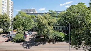A street view with parked cars, trees, and buildings. - Metro Młynów Comfort Apartment (Warszawa)