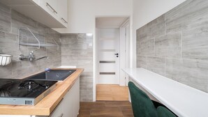 A narrow kitchen with a black stove, white cabinets, and a wooden countertop. - Złota Warsaw Skyline Apartment (Warszawa)