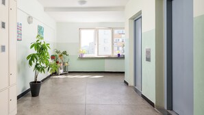 Ein Flur mit einem Blumentopf, einem Fenster mit Blick auf Gebäude und einer Tür.