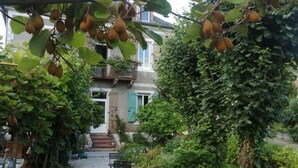 Un jardin agrémenté d’une pergola, d’un banc et d’un bâtiment doté d’un balcon.