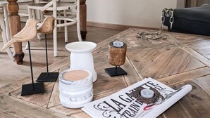 Un coin repas avec une table en bois, des chaises, un miroir et un magazine posé sur le sol.