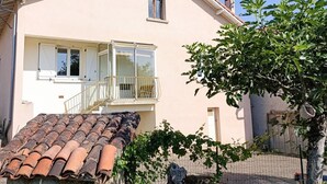 Een huis met twee verdiepingen, een balkon, een pannendak en een klein raam.