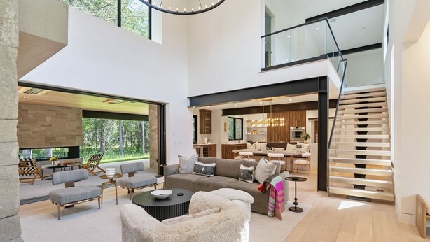 A spacious living area with a modern sofa set, a fireplace, and a dining area with a kitchen in the background. - RMR: Tensleep Oasis Home in The Aspens/Wilson,WY (Wilson)