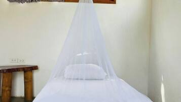 Une chambre avec un lit recouvert d’un dais blanc, une couvre-lit à motifs, un banc en bois et une fenêtre donnant sur un paysage verdoyant.