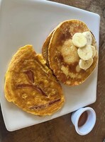 A plate with two pancakes and sliced bananas on a white plate.
