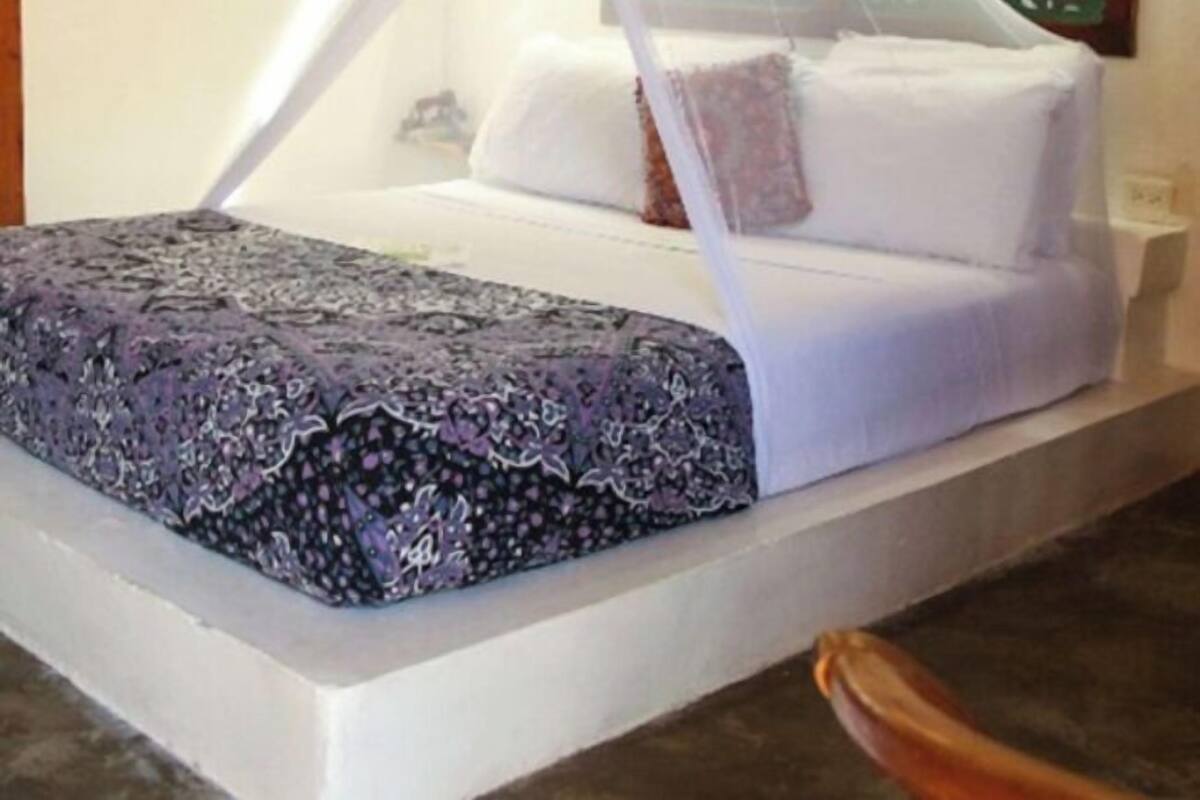A bed with a canopy, white bedding, and a patterned throw.