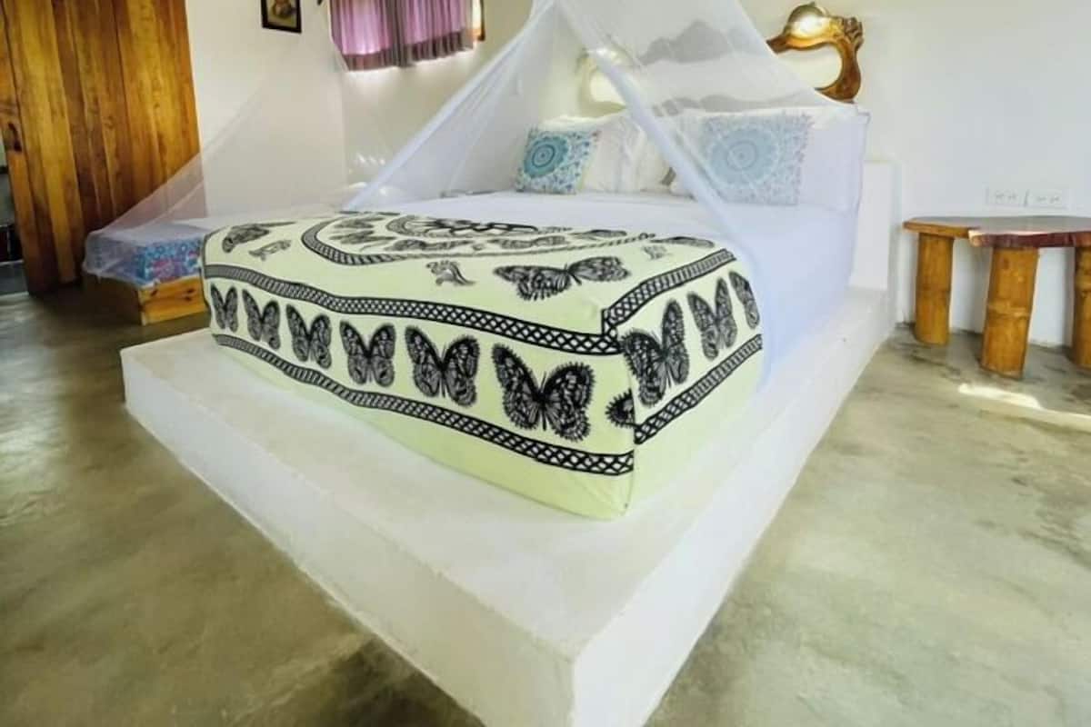 A bedroom with a bed, a window, and a wooden floor.