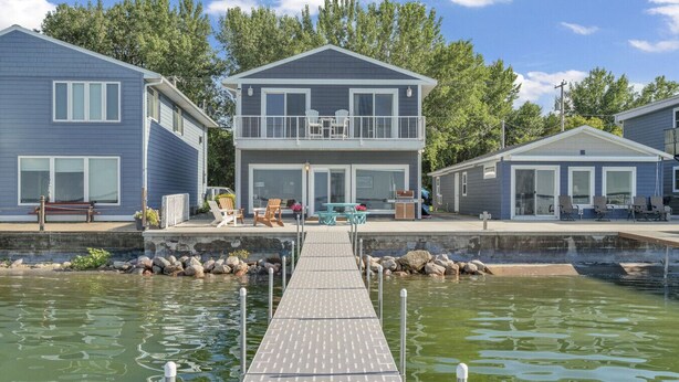 A waterfront property with a dock leading to a house with a balcony and outdoor seating. - NEW LISTING...AWave From It All - Lakefront on Big Spirit Lake (Orleans)
