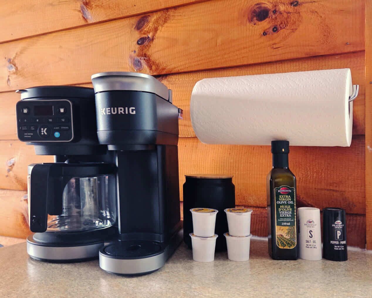A Keurig coffee maker, a roll of paper towels, and various condiments on a kitchen counter.