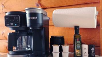 A Keurig coffee maker, a roll of paper towels, and various condiments on a kitchen counter.