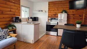 Une cuisine compacte avec un îlot central, une table à manger avec des chaises et un téléviseur fixé au mur.