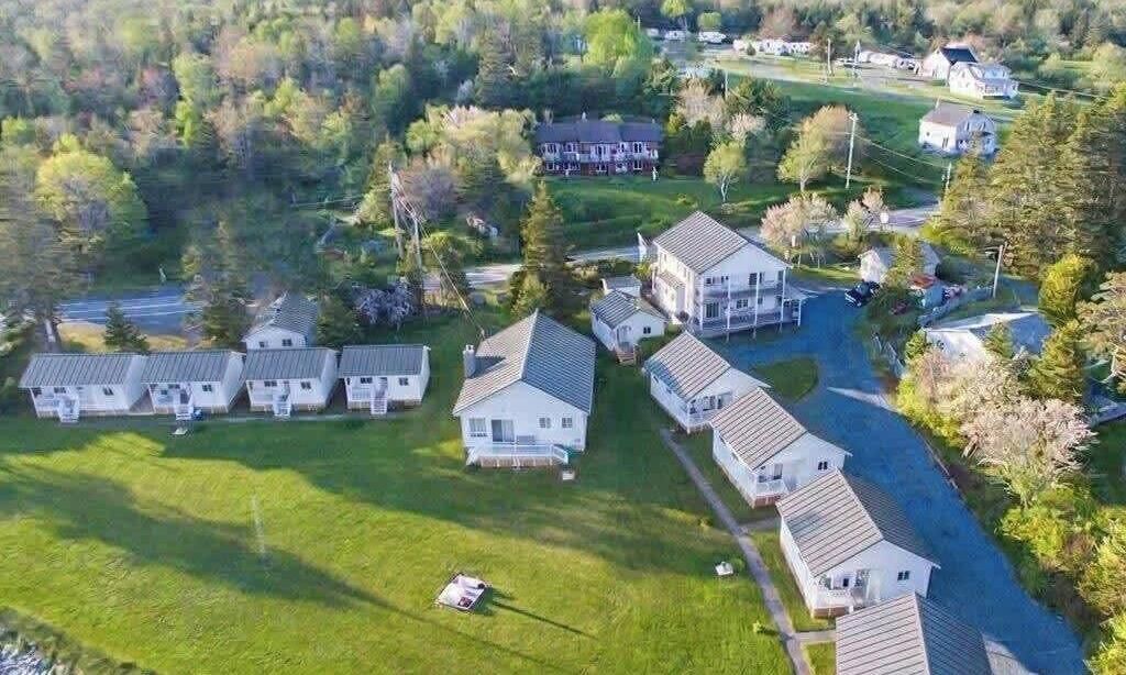 A residential area with multiple houses, a large house with a porch, and a well-maintained lawn.